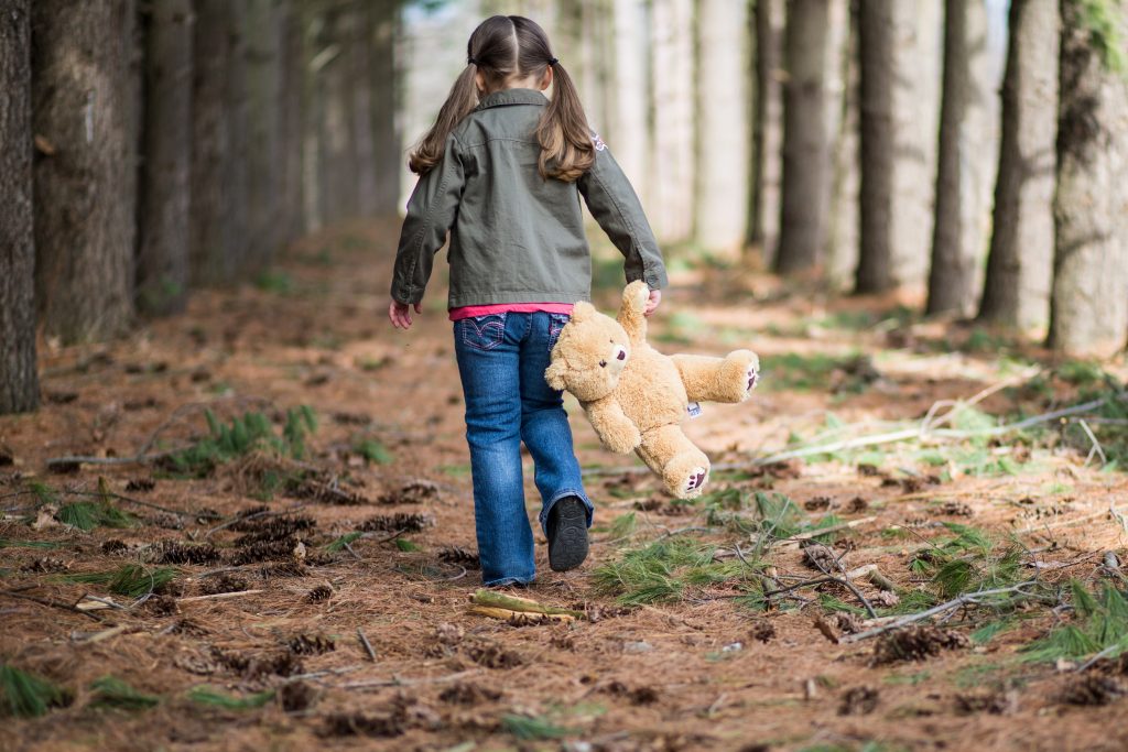 Healthy Huron Hunt Team - a young girl walking through the woods holding her stuffed plush bear