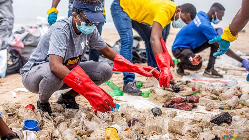 A clean-up crew gathering garbage on a beach for World Clean Up Day