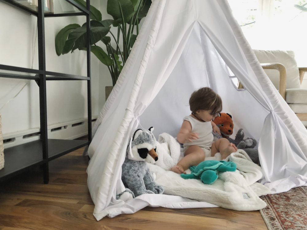 A child with stuffed plush buddies in a tent