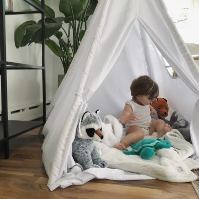 A child with stuffed plush buddies in a tent