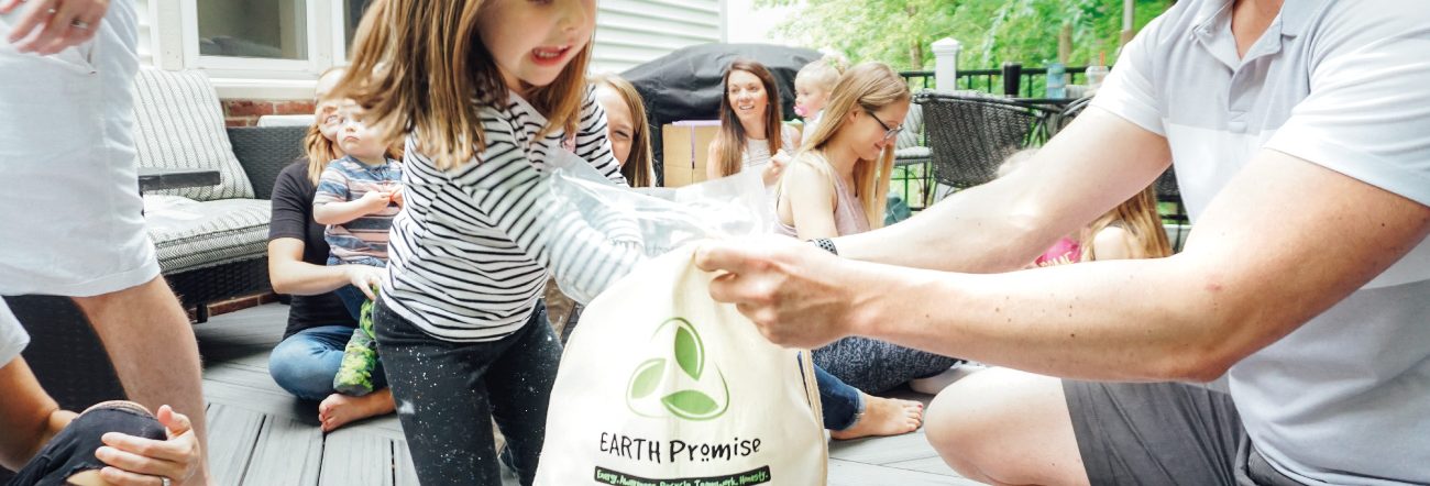 A man giving a child a bag with Earth-friendly, sustainable plush