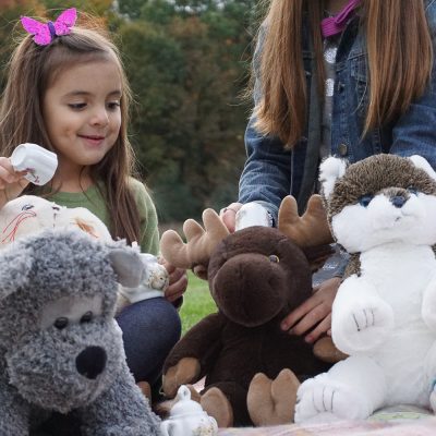 Two children playing with plush animals. There is a bear, moose, and husky dog plush. Please review and complete the Media Policy Agreement form for consideration of the use of our materials.